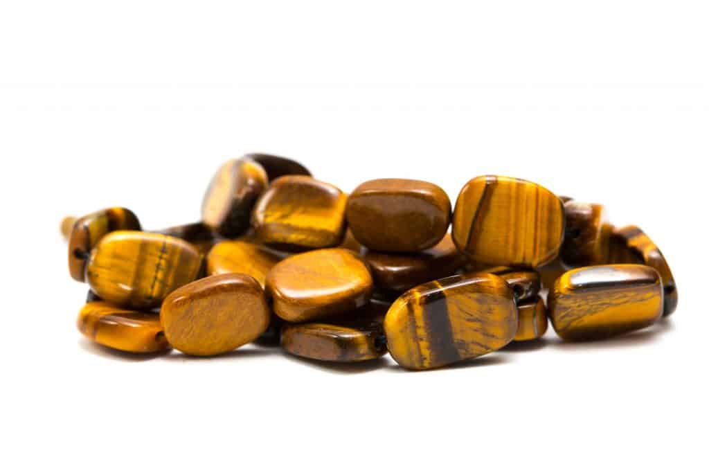 Beads and necklaces made of amber colored semi-precious stones with tiger eyes. Background of beautiful mother-of-pearl jewelry coral color, bright orange stones, amber, cat's eyes.